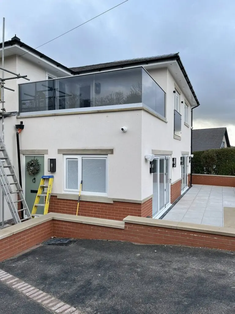 Modern rendered house with glass balcony railing and patio